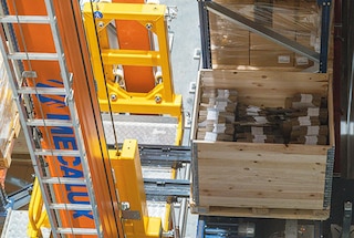 Išėmimo sistema paima padėklą ir padeda jį ant keliamosios platformos