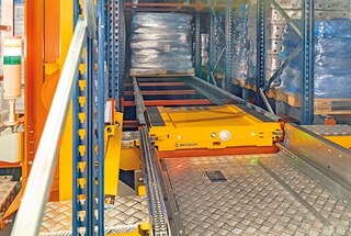 Padėklas grąžinamas ant automatinio aukštųjų stelažų krautuvo padėklams, kad būtų pervežtas į prieigos vietą