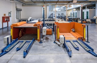 Hidrauliniai pakeliamieji stalai perkelia krovinius nuo grindų lygio iki padėklų konvejerio